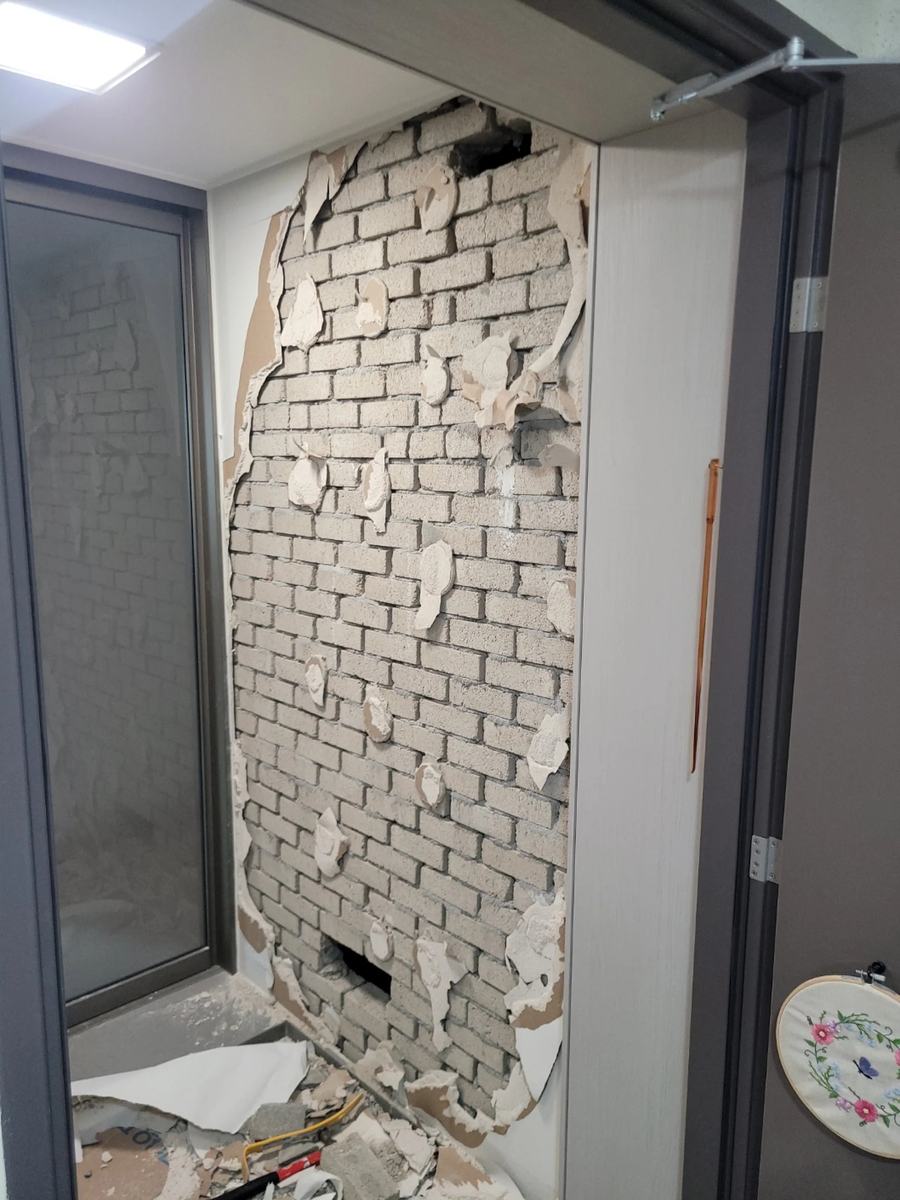 철거 전 마감재가 뜯겨 벽돌이 드러난 벽면 사진
